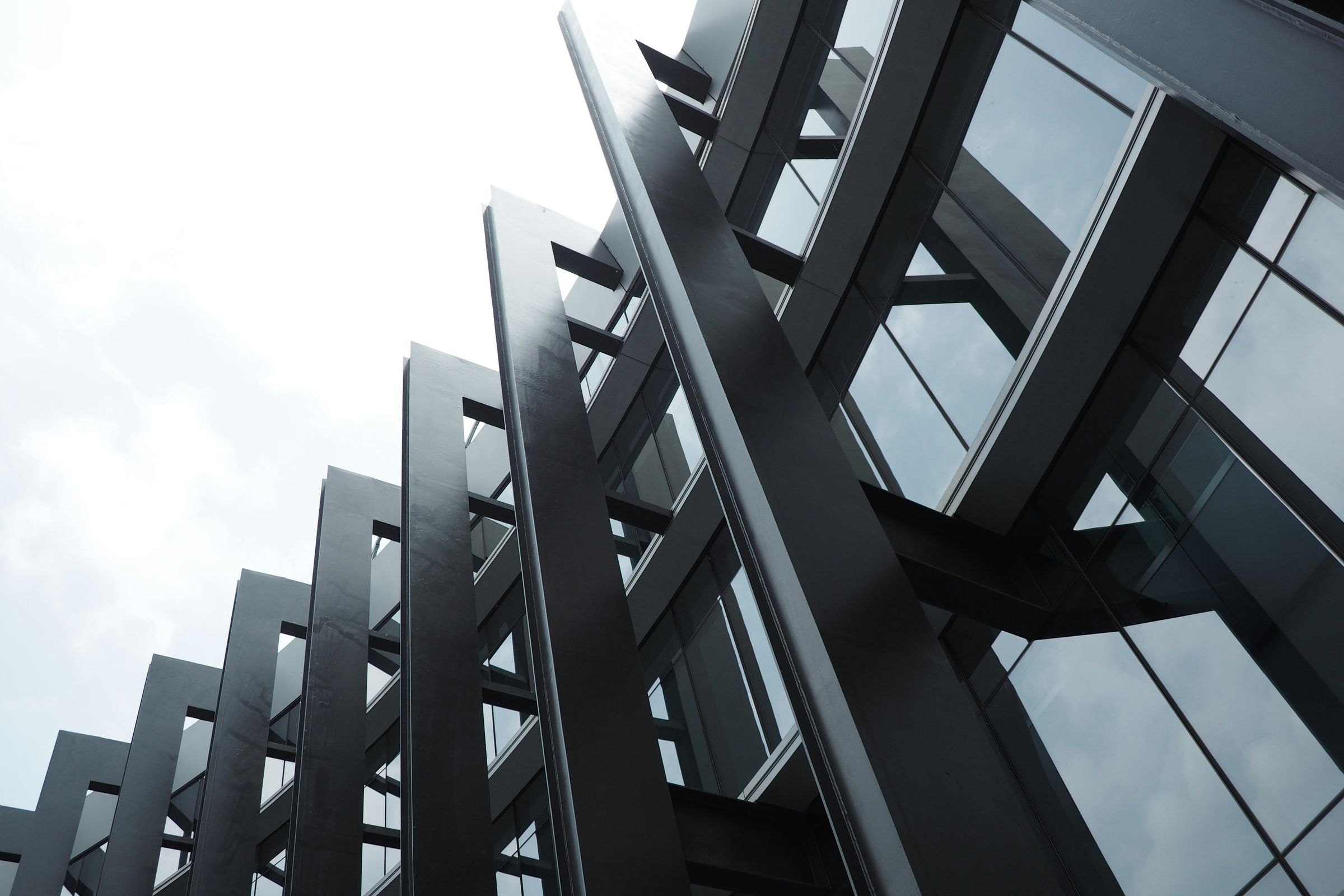 Angular steel and glass building facade against a pale sky